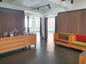 Eingangsbereich-Studio 13 Holztheke mit Geschirr darauf links, rechts Sofaecke vor brauner Wand